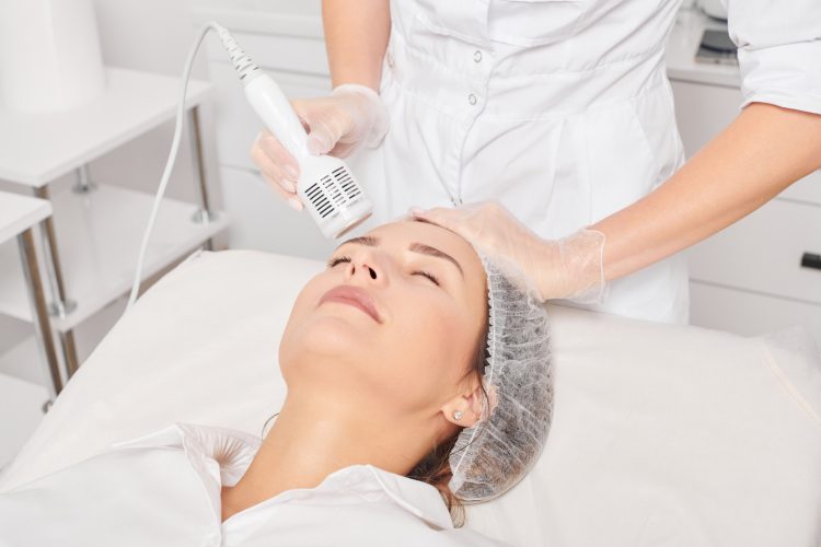 beautician makes cryotherapy for rejuvenation woman face, anti aging procedure in salon